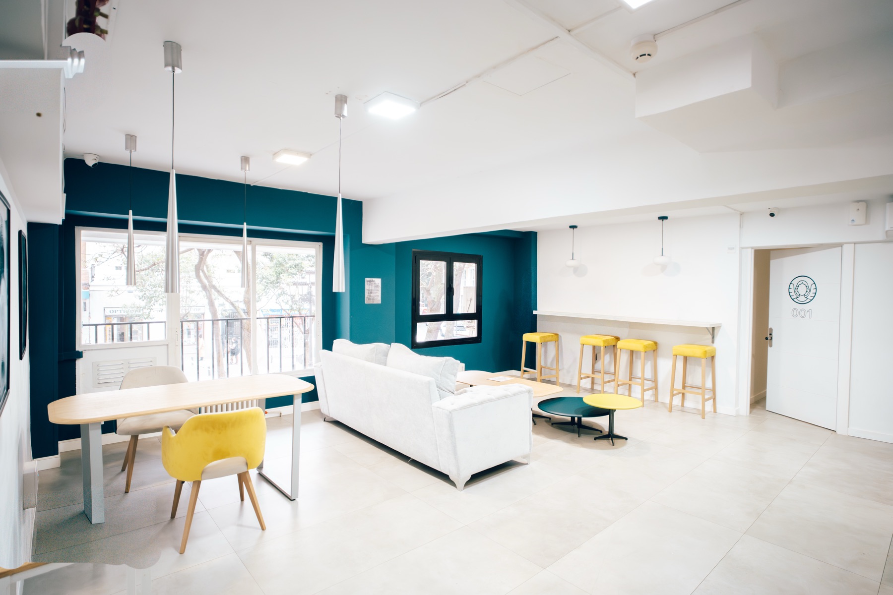 Salón común de MadVibes con sofá blanco y pared azul